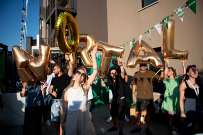 Nortal Bulgaria employees holding gold balloon letters spelling “Nortal” during a summer team event..
