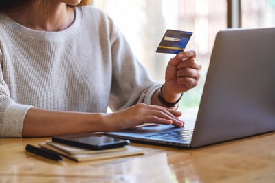Woman holding credit card while using laptop