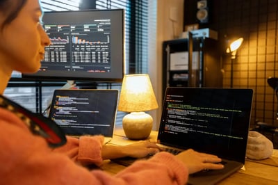 Developer working on code and analytics dashboards across multiple screens in a modern workspace